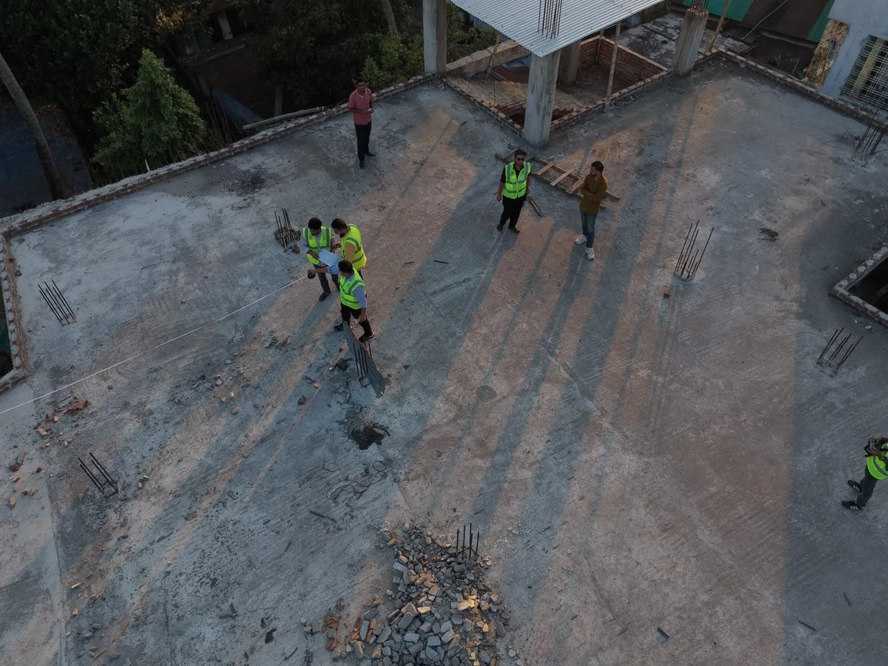 Aerial view of a flat concrete rooftop in Natore with the eBiddut team in high-visibility vests measuring it