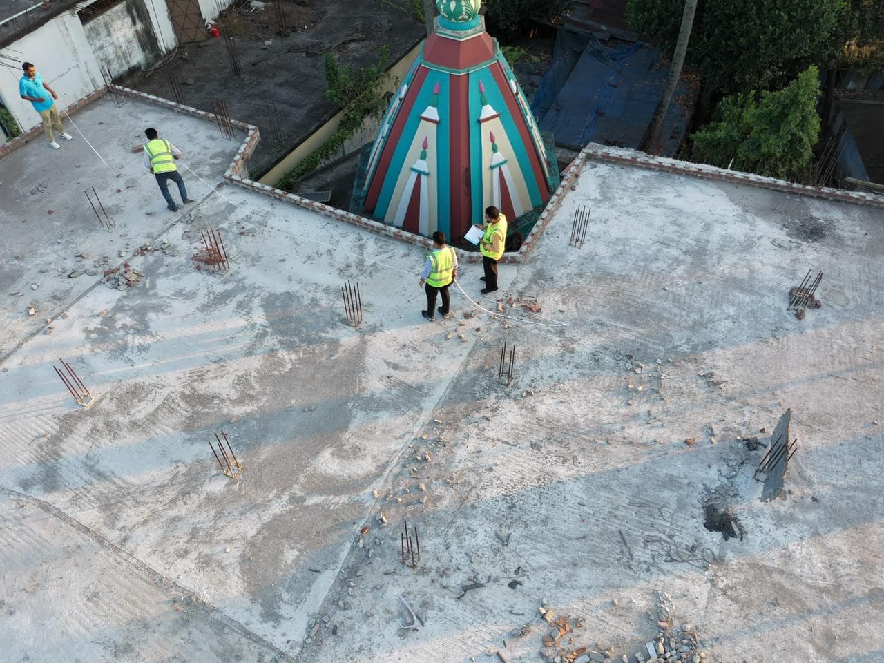 Aerial view of the team measuring a rooftop beside a painted temple spire