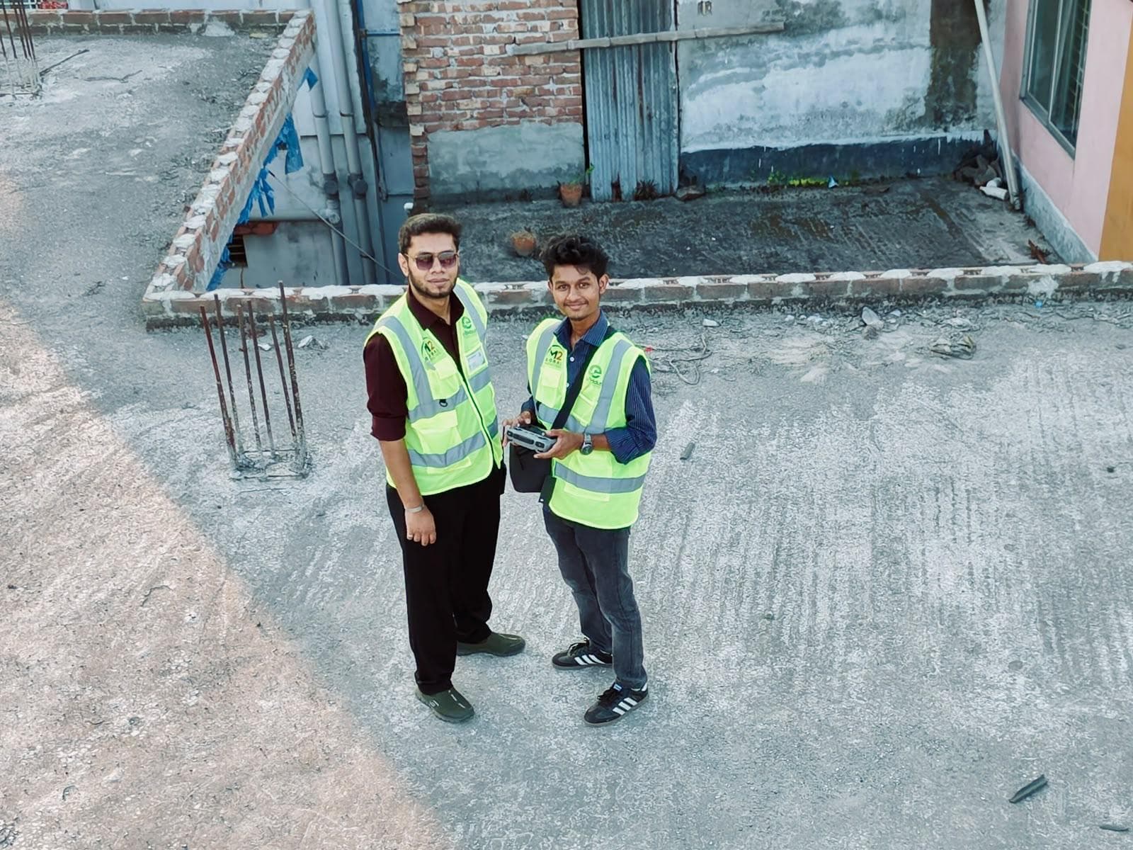 Two eBiddut team members on a rooftop, one holding the drone controller