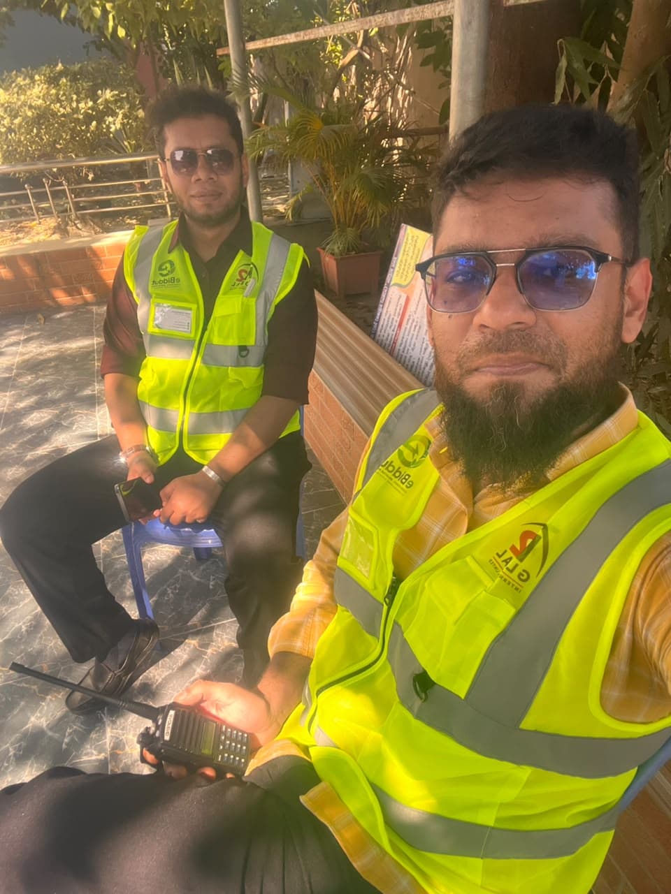 Two eBiddut team members in vests taking a short break between site visits